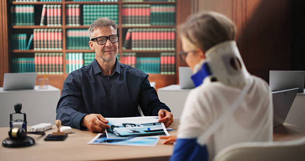 Experienced attorney reviewing accident case photographs with an injured client wearing a cervical collar